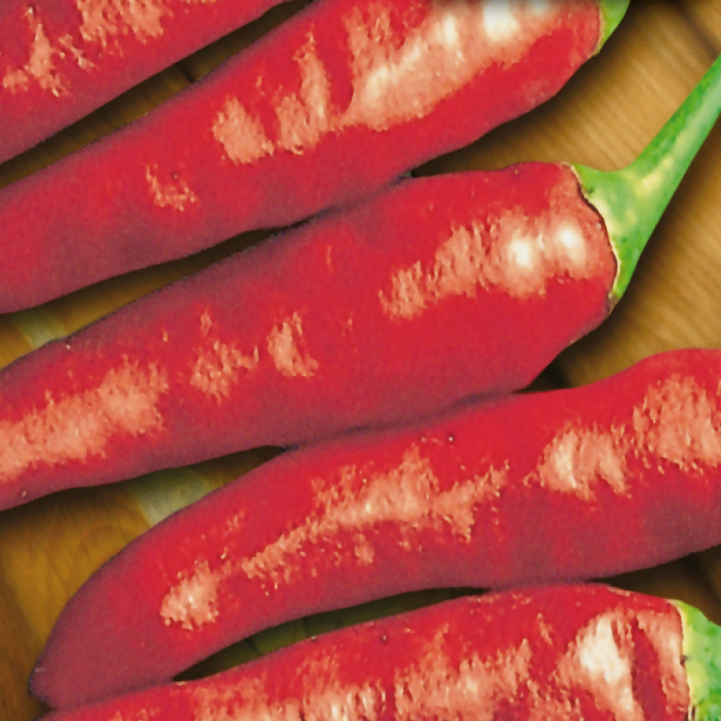 A group of bright red chili peppers with green stems, arranged on a surface.