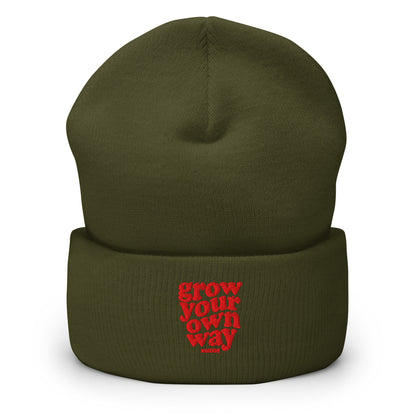 An olive green knit beanie hat with a folded cuff, featuring red embroidered text that reads 'grow your own way', shown on a plain white background.