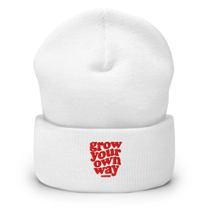 A white knit cuffed beanie hat with red text on the front cuff reading 'grow your own way' underneath, shown on a clean white background.