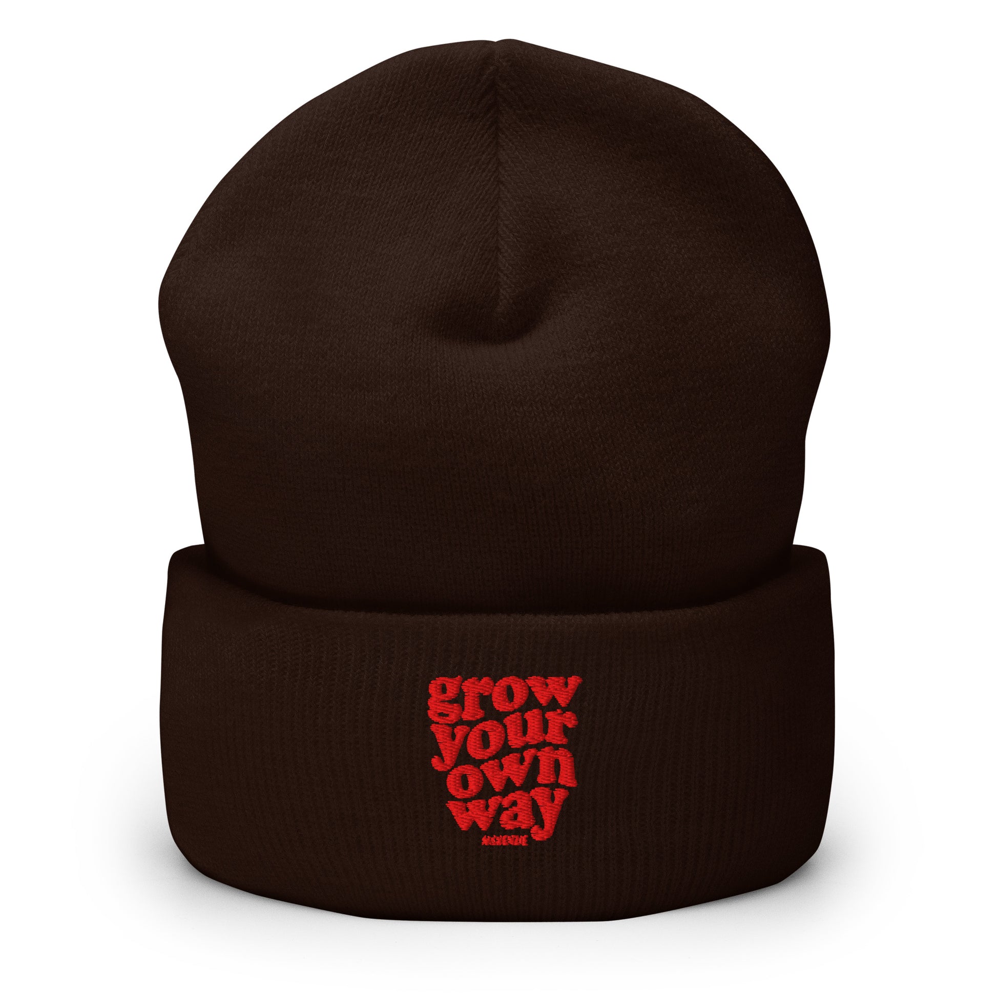 A dark brown knit beanie hat with a folded cuff, featuring the phrase 'grow your own way' embroidered in red on the front cuff.