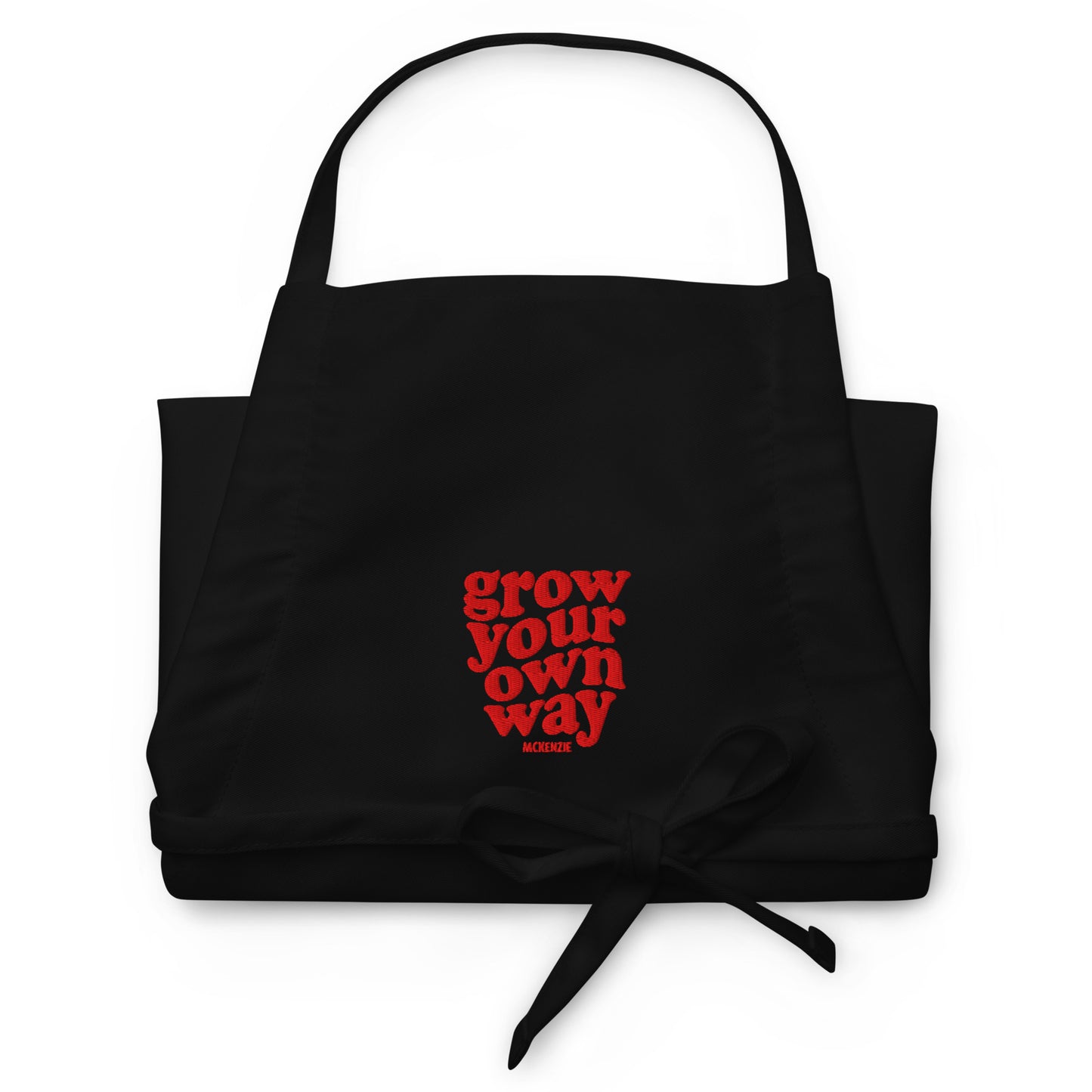 Black apron with red text 'grow your own way' on a white background