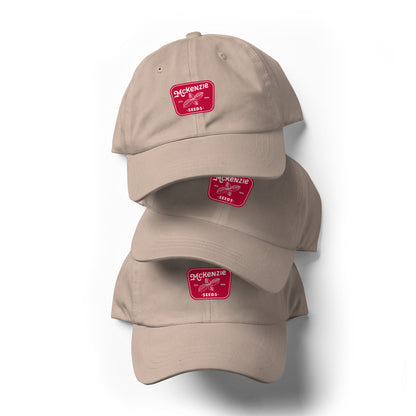 Three light beige baseball caps with a red logo and text saying 'McKenzie Seeds' on the front. 