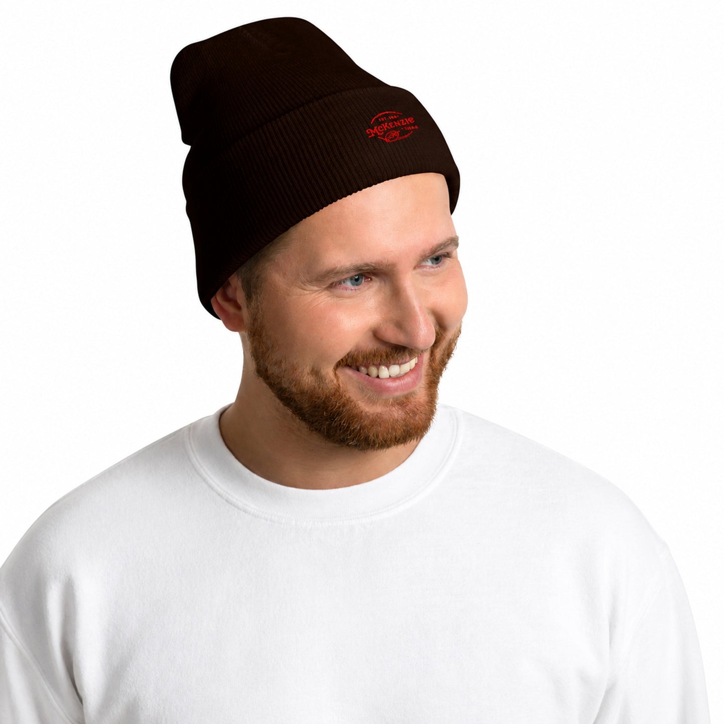 Man wearing a black beanie with red logo against a light gray background