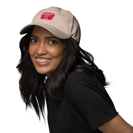 A light beige baseball cap with a red logo and text saying 'McKenzie Seeds' on the front. 